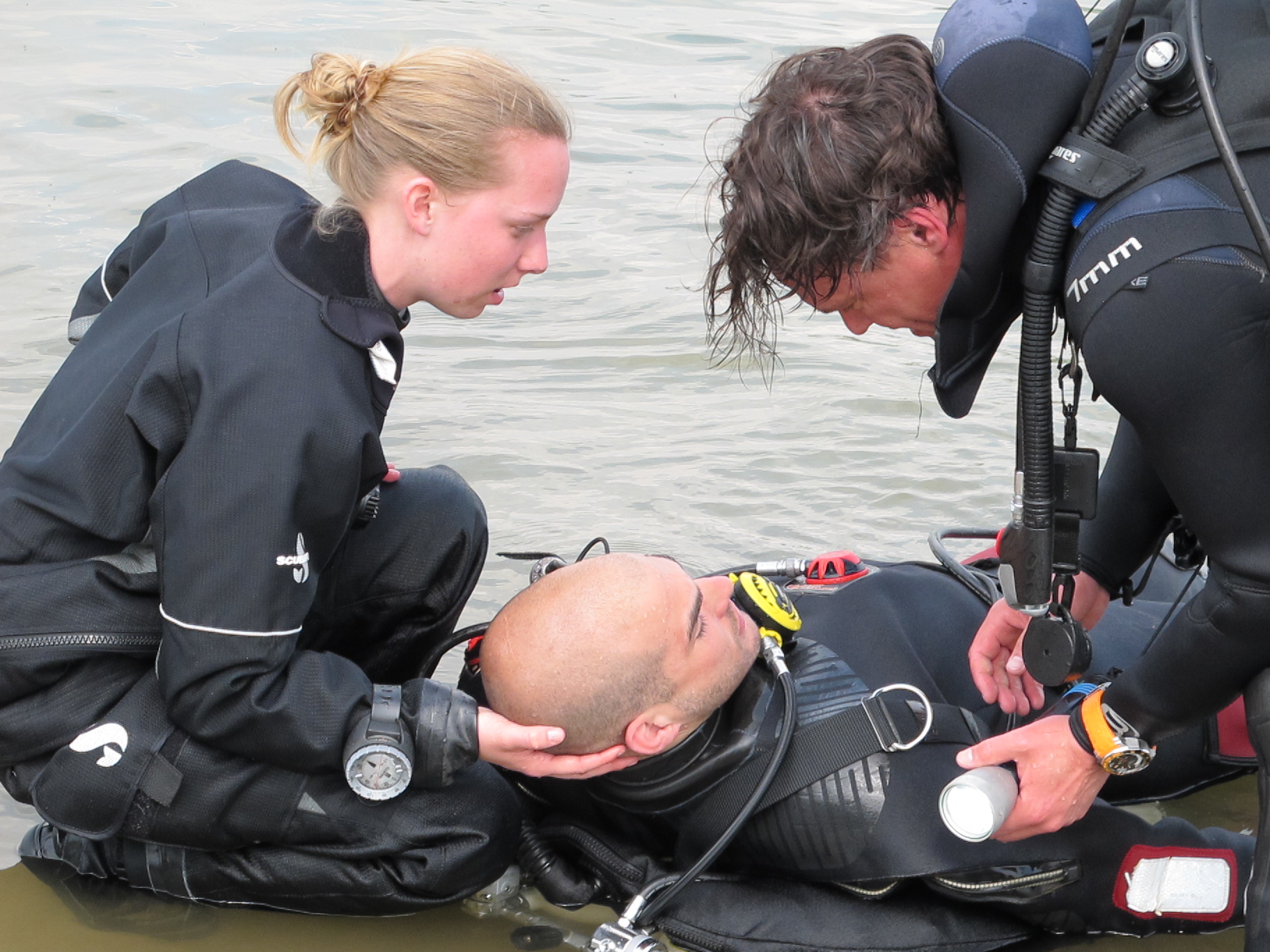 2 duikers helpen gewonde duiker die op zijn rug ligt