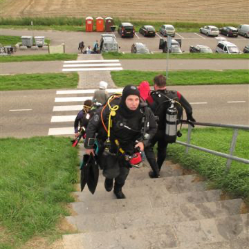 Duikers beklimmen hoge trap over duik in Zeeland naar Grevelingenmeer