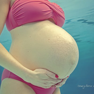 Zwangere vrouw staat in bikini in het water